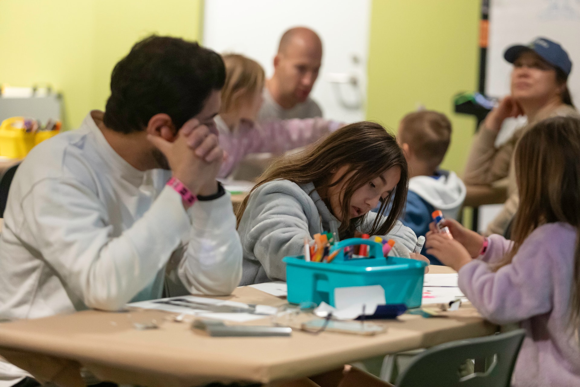 Family sitting at workshop craft table drawing with markers