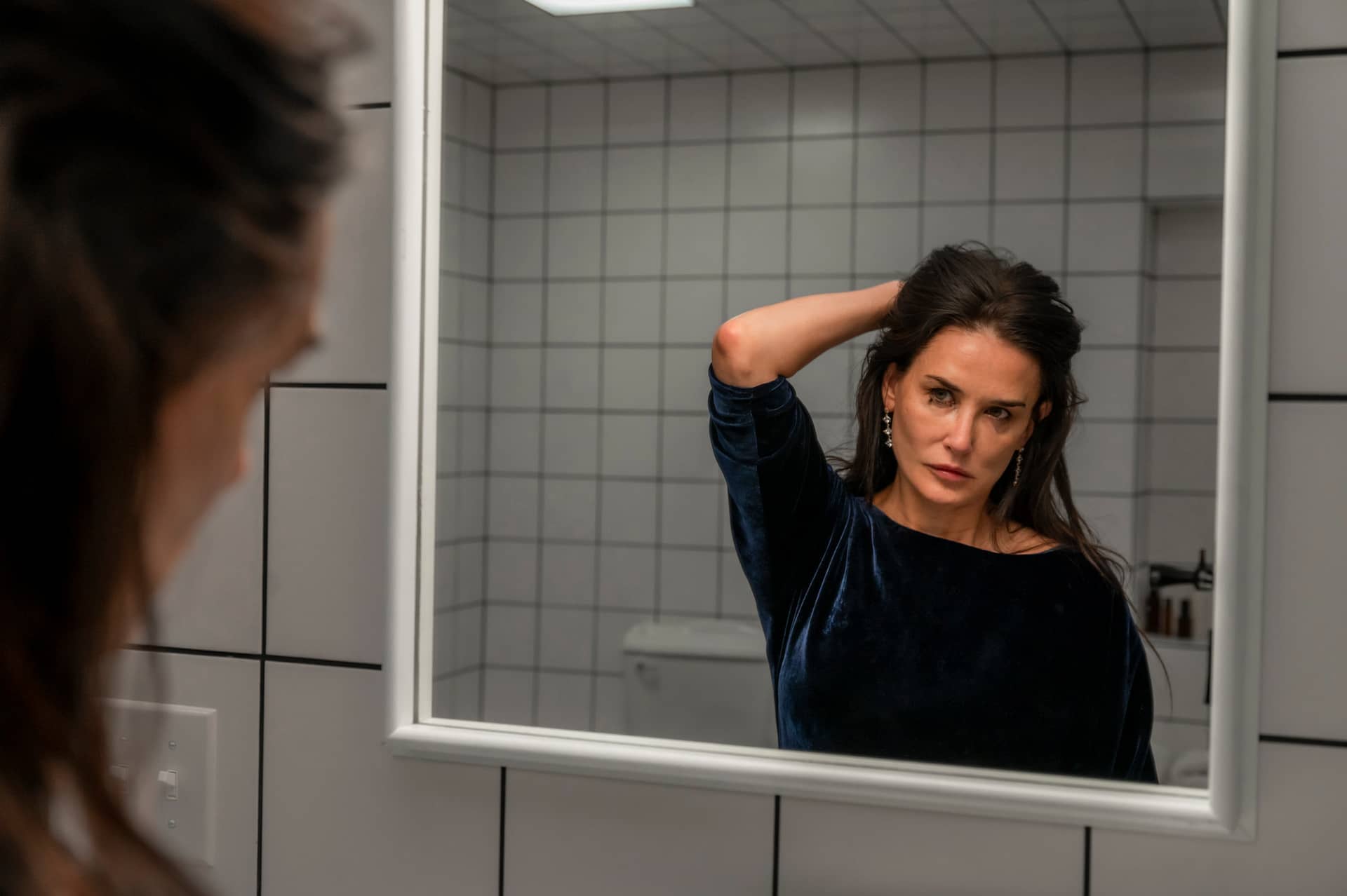 Demi Moore looking at herself in bathroom mirror