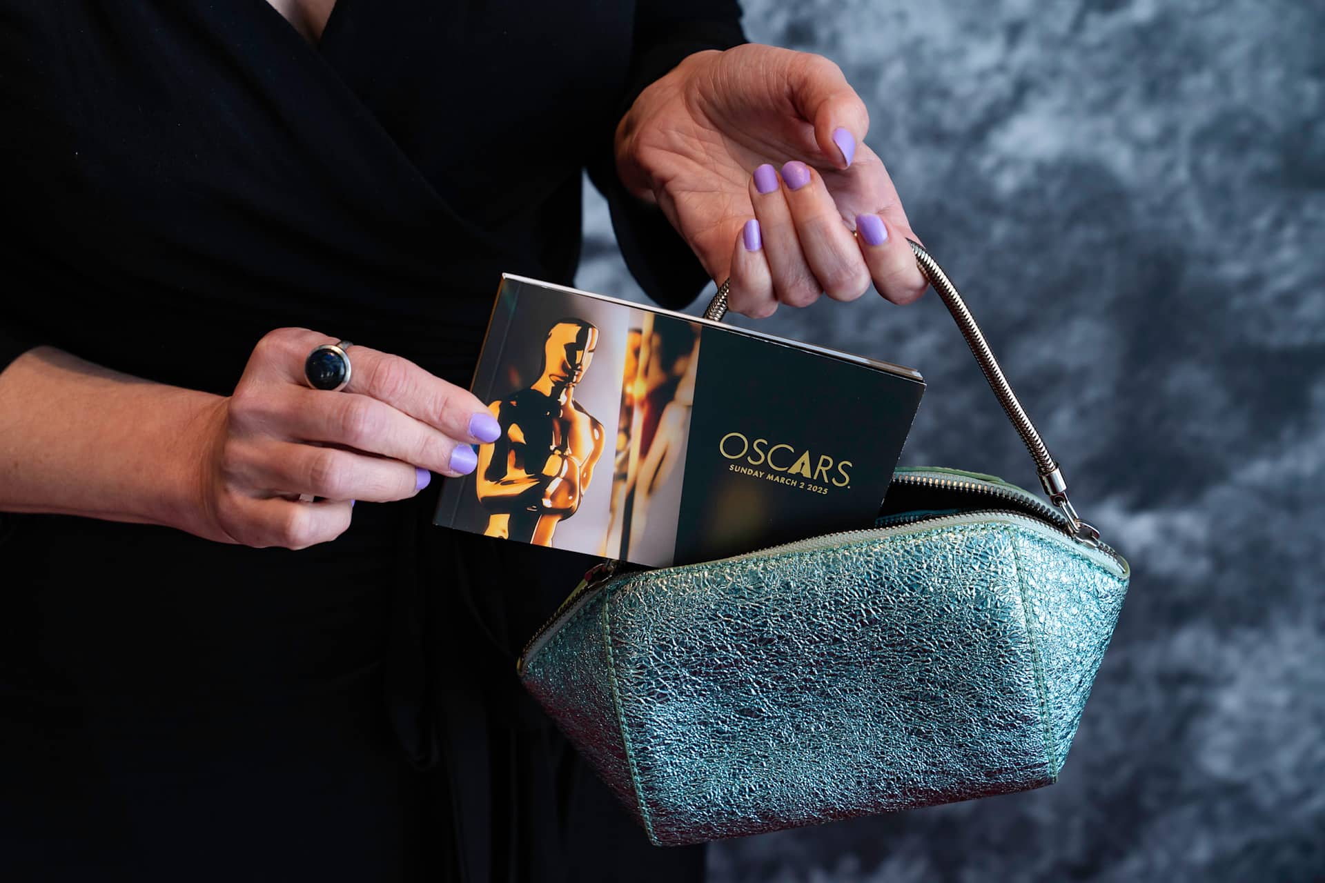 A women pulling out a 2025 Oscars handbag from a purse
